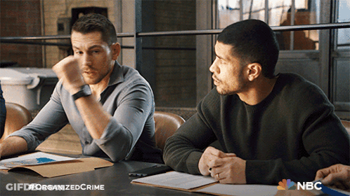 Two Men Sitting At A Table With A Nbc Logo On The Table GIF