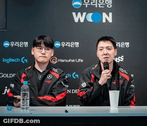 Two Men Sitting At A Table With A Sign That Says Won GIF