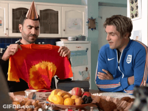 Two Men Sitting At A Table With One Wearing A Nike Jacket GIF