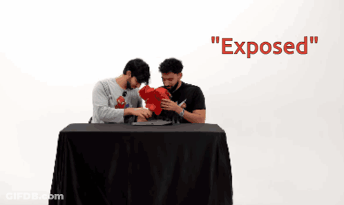 Two Men Sitting At A Table With The Word Exposed On The Wall GIF