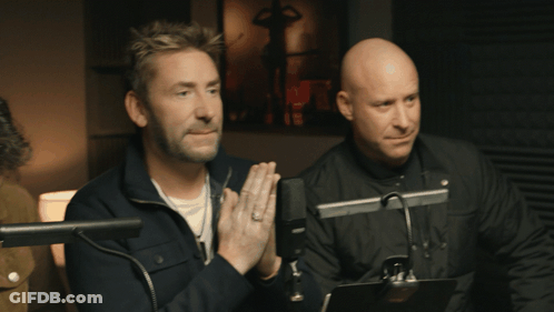 Two Men Sitting At Microphones With Hands Folded GIF