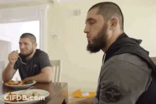 Two Men Sitting At Table Eating Food One With Beard GIF