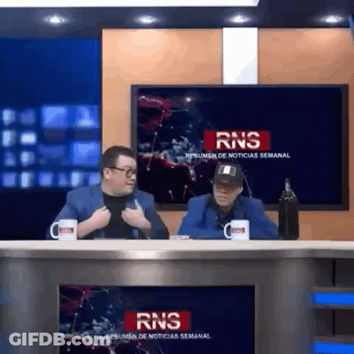 Two Men Sitting At Table In Front Of RNS Sign GIF