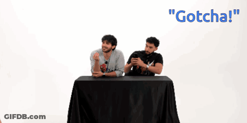 Two Men Sitting At Table One Wearing Gotcha Shirt GIF