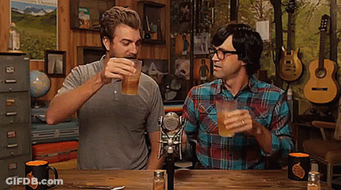 Two Men Sitting At Table Toasting Beer GIF