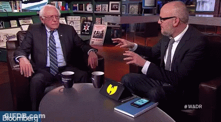Two Men Sitting At Table With Bloomberg GIF