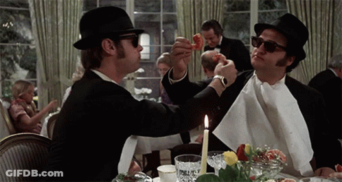 Two Men Sitting At Table With Candle And Napkin GIF