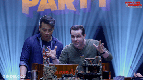 Two Men Sitting At Table With Dungeons & Dragons Sign GIF