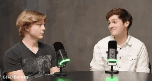 Two Men Sitting At Table With Microphones GIF