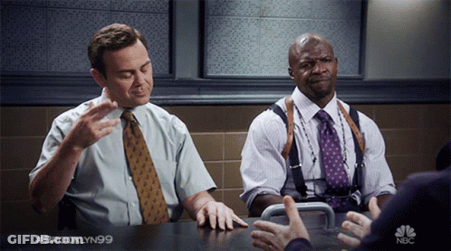 Two Men Sitting At Table With NBC GIF