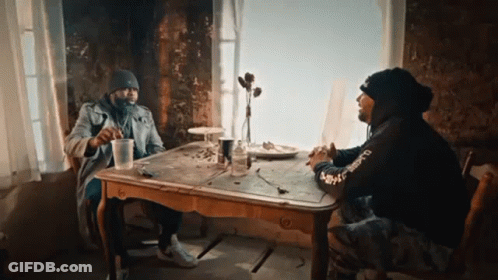 Two Men Sitting At Table With Supreme Sweatshirt GIF