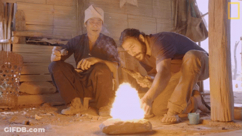 Two Men Sitting By Fire With National Geographic Logo GIF