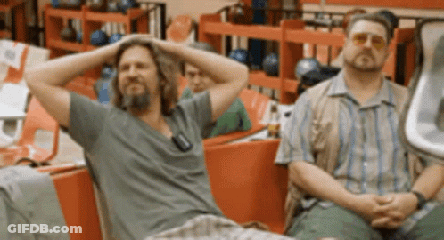 Two Men Sitting In A Bowling Alley With Their Hands On Their Heads GIF
