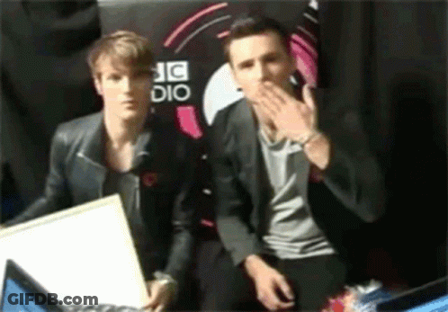 Two Men Sitting In Front Of A Sign That Says Dj Dio GIF