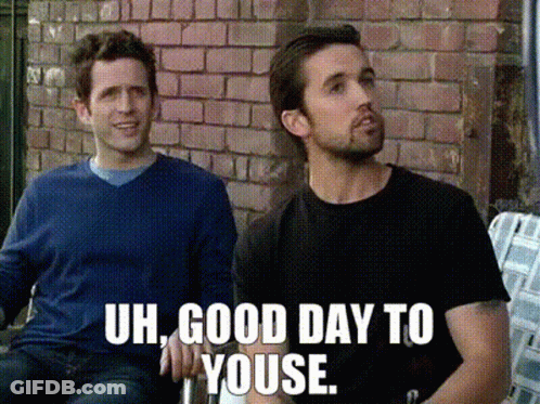 Two Men Sitting In Front Of Brick Wall Saying Uh Good Day To Youse GIF