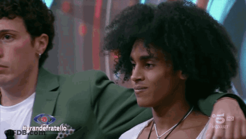 Two Men Sitting In Front Of #GrandeFratello Screen GIF
