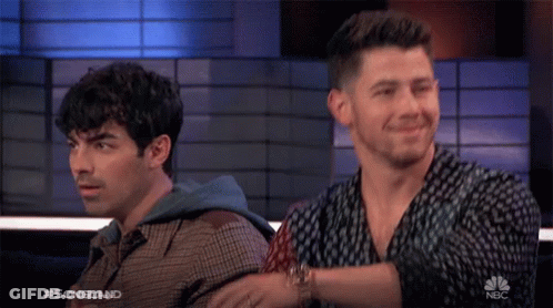 Two Men Sitting Next To Each Other On A Nbc Show GIF