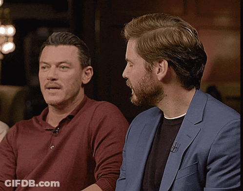 Two Men Sitting Next To Each Other One In Blue Suit GIF