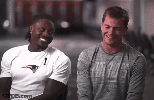 Two Men Sitting Next To Each Other One Wearing Patriots Shirt GIF
