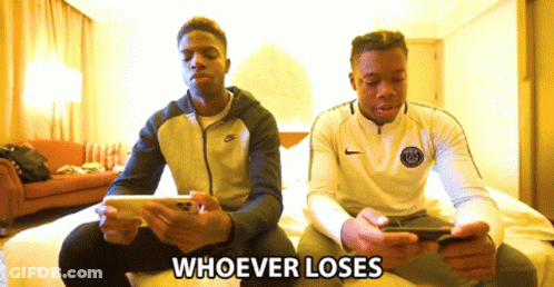 Two Men Sitting On A Bed Looking At Their Cell Phones With The Words Whoever Loses Behind Them GIF