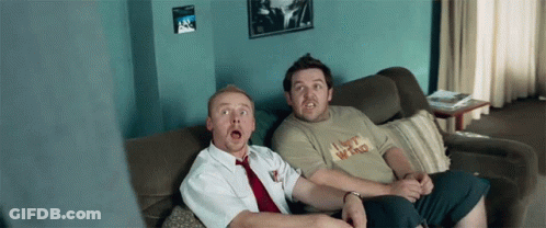Two Men Sitting On A Couch One Of Whom Is Wearing A Shirt That Says I Bet Who GIF