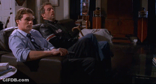 Two Men Sitting On A Couch With Their Feet Up GIF