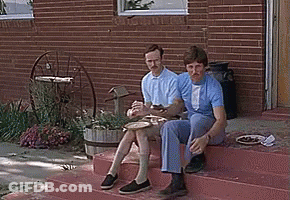 Two Men Sitting On Brick Steps Eating GIF