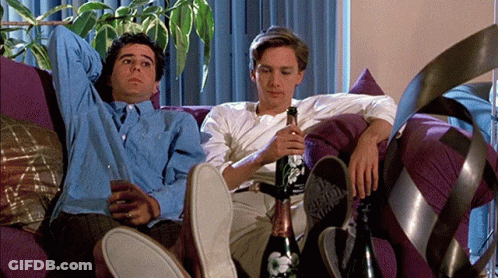 Two Men Sitting On Couch Holding Bottle And Glass GIF