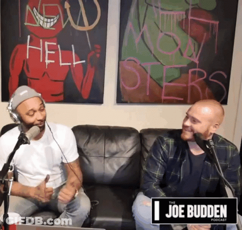 Two Men Sitting On Couch In Front Of Joe Budden Sign GIF