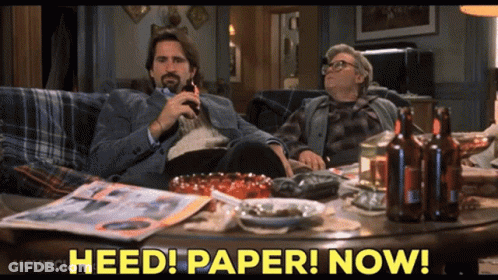Two Men Sitting On Couch Saying Heed Paper Now GIF