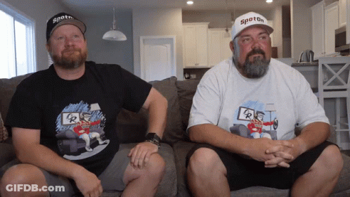 Two Men Sitting On Couch Wearing Spoton Shirts GIF