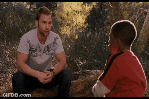 Two Men Sitting On Log Talking In Woods GIF