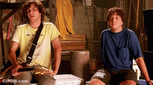 Two Men Sitting One Holding Guitar Other Wearing Everlast Shirt GIF