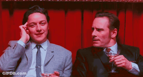Two Men Sitting One Holding Martini Glass GIF