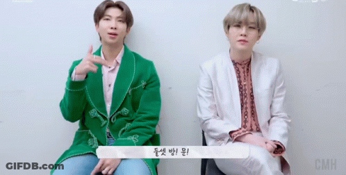 Two Men Sitting, One In Green Jacket GIF