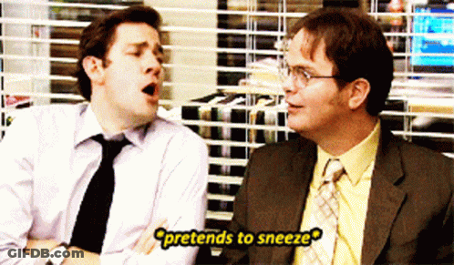 Two Men Sitting One Pretending To Sneeze GIF