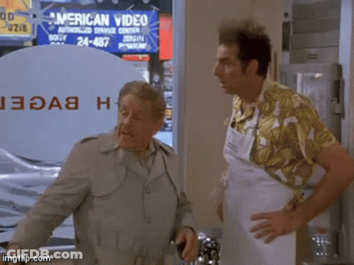 Two Men Stand In Front Of An American Video Sign GIF