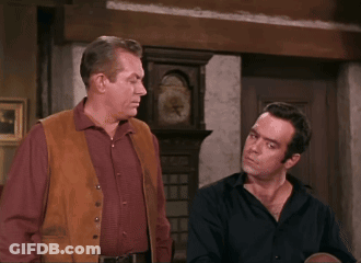 Two Men Standing Beside Large Clock GIF