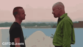 Two Men Standing By Water, One In Green Shirt GIF
