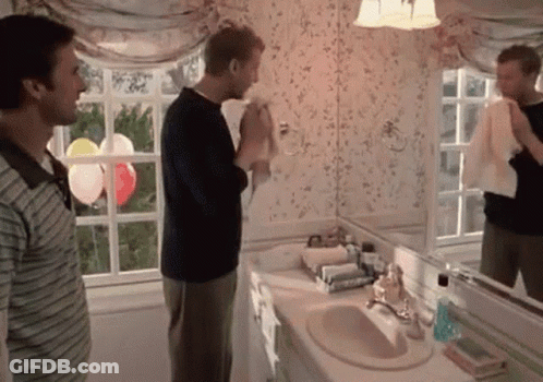 Two Men Standing In A Bathroom With Balloons In The Window GIF