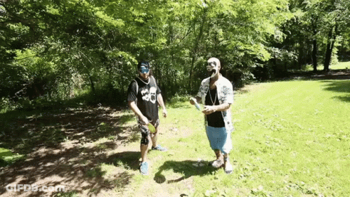 Two Men Standing In A Grassy Field With One Wearing A Shirt That Says 36 GIF