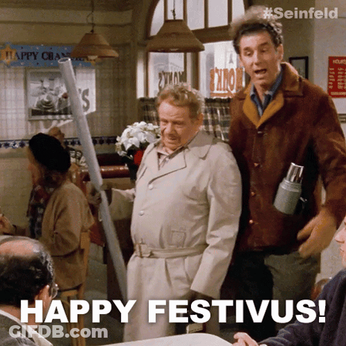 Two Men Standing In A Restaurant With The Words Happy Festivus On The Bottom GIF