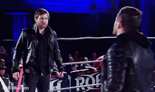 Two Men Standing In A Wrestling Ring With A Sign That Says Rock GIF