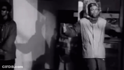 Two Men Standing In Black And White Room GIF