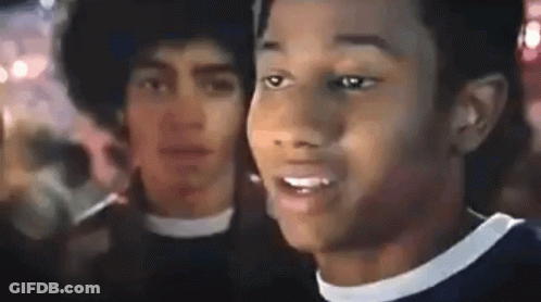 Two Men Standing In Crowd One With Afro GIF
