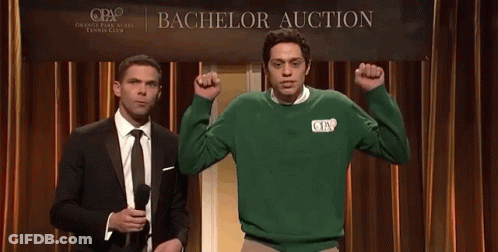 Two Men Standing In Front Of A Bachelor Auction Banner GIF