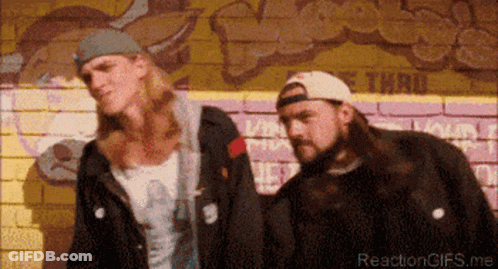 Two Men Standing In Front Of A Brick Wall With Graffiti On It GIF