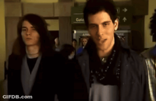 Two Men Standing In Front Of A Green Sign That Says Gates GIF