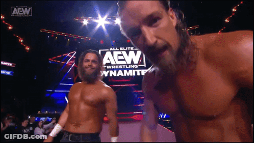 Two Men Standing In Front Of A Sign That Says Aew GIF