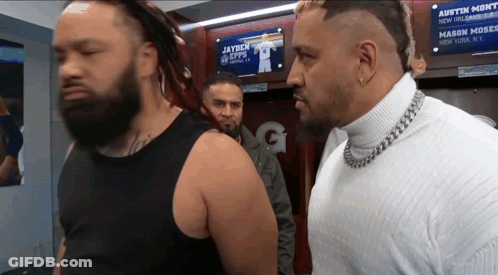 Two Men Standing In Front Of A Sign That Says Austin Monti GIF